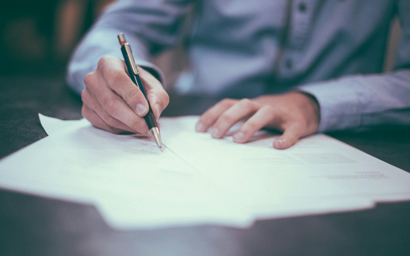 Bookkeeper signing paperwork at a desk